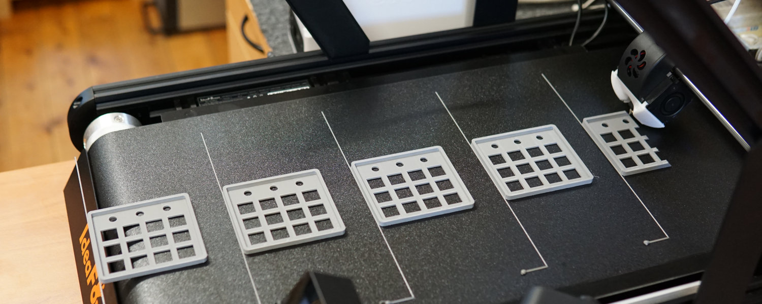 A 3D printer setup featuring multiple of the same product on a moving belt bring printed for production use.