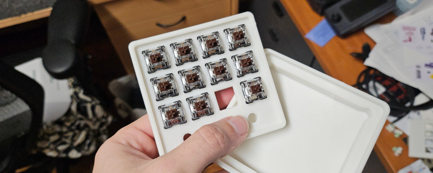 A person holds a small tray filled with mechanical key switches, showcasing a prototype sim racing button pad design.