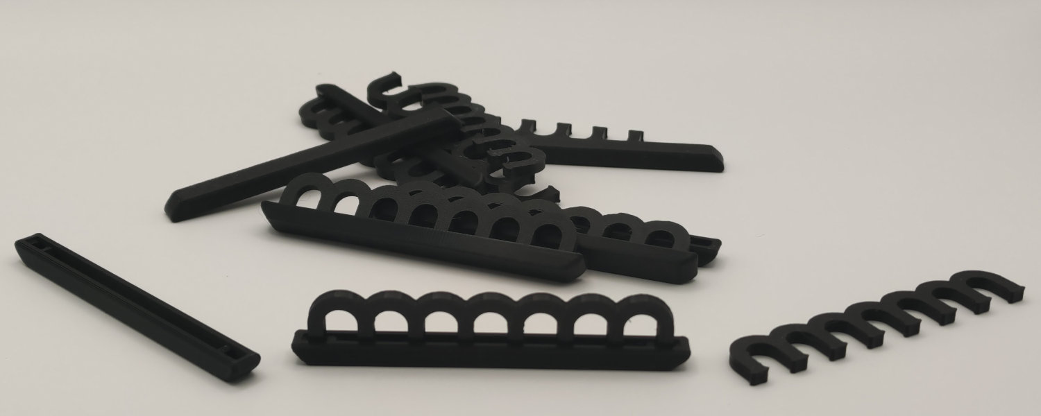 A cluster of black plastic clips arranged on a white surface, showcasing their simple design and functionality.