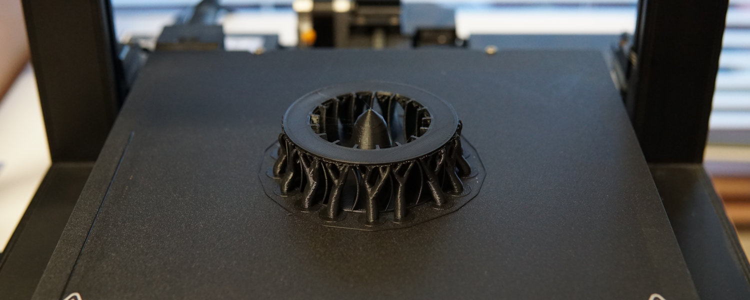 A 3D printer equipped with a fan above it, illustrating the technology used for enhanced printing efficiency.