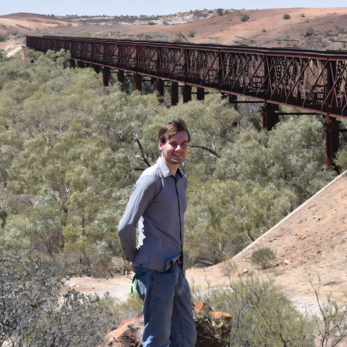 A portrait shot of Bradley Turner standing in front of Algebuckina Bridge